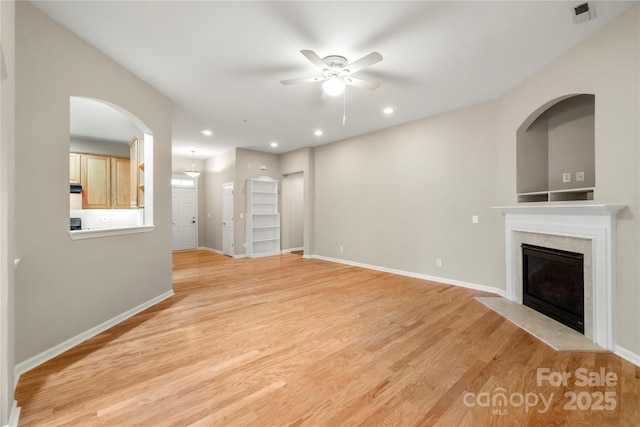 unfurnished living room with light wood-style floors, baseboards, a fireplace, and visible vents