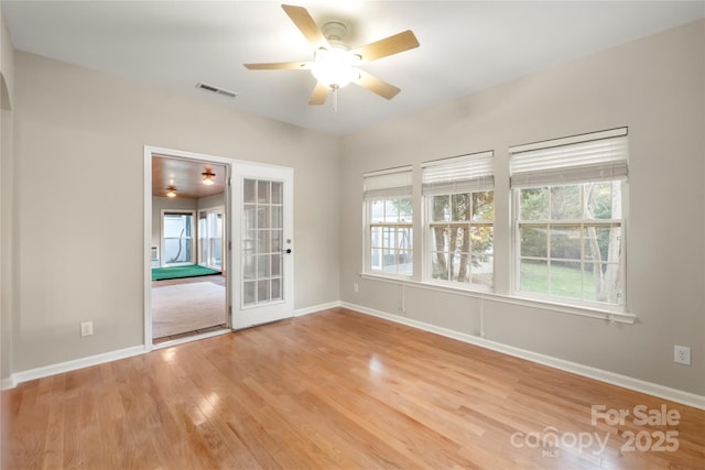 spare room with french doors, visible vents, ceiling fan, wood finished floors, and baseboards