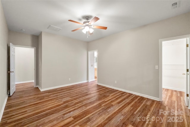 spare room featuring wood finished floors, visible vents, and baseboards