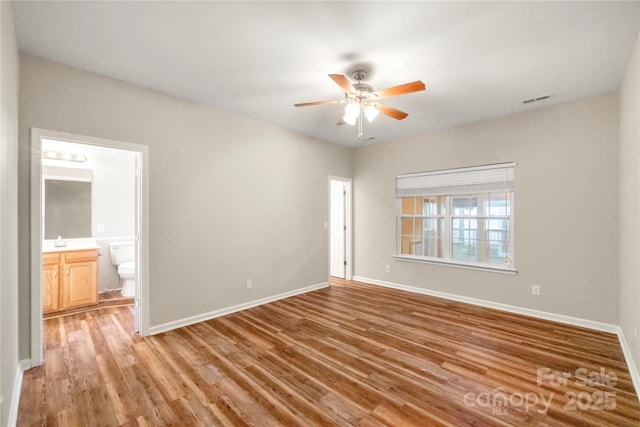 unfurnished bedroom featuring visible vents, light wood-style floors, connected bathroom, a sink, and baseboards