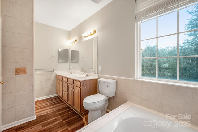 full bath featuring a sink, a tub, tile walls, and wood finished floors