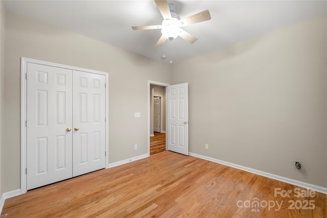 unfurnished bedroom with ceiling fan, a closet, light wood-type flooring, and baseboards