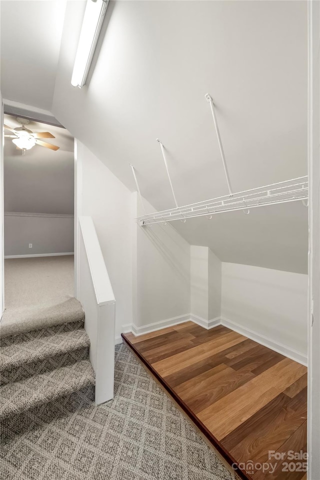 walk in closet with a ceiling fan, vaulted ceiling, and wood finished floors