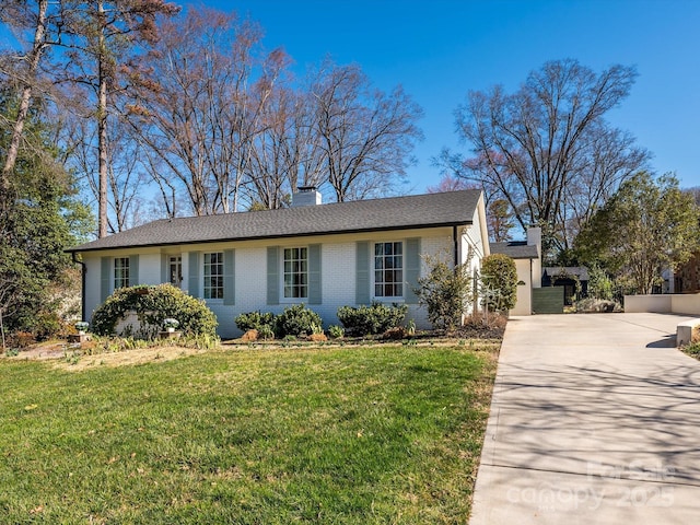 ranch-style home with concrete driveway, brick siding, a front lawn, and a chimney