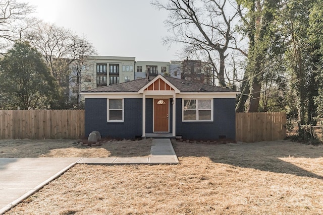 bungalow-style home with fence and brick siding