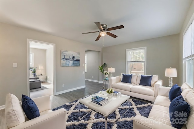 living room featuring ceiling fan, wood finished floors, and baseboards