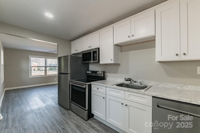 kitchen featuring appliances with stainless steel finishes, white cabinetry, a sink, and light wood finished floors