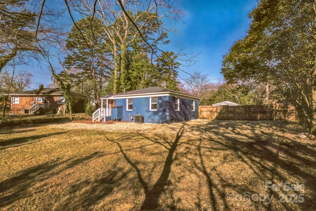 exterior space with central AC unit, fence, and a yard