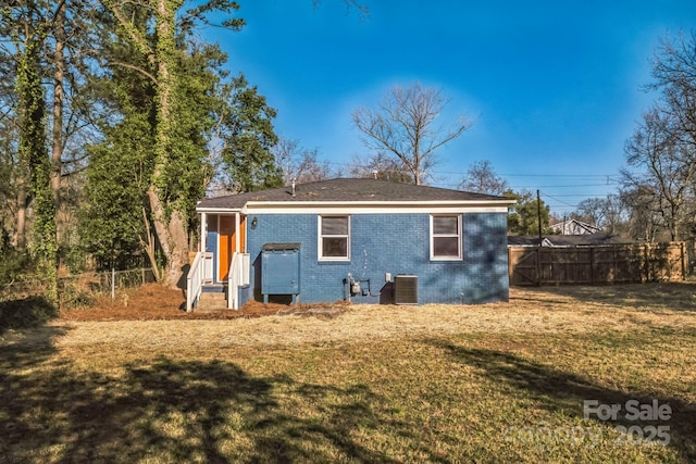 rear view of property featuring a yard, a fenced backyard, cooling unit, and brick siding