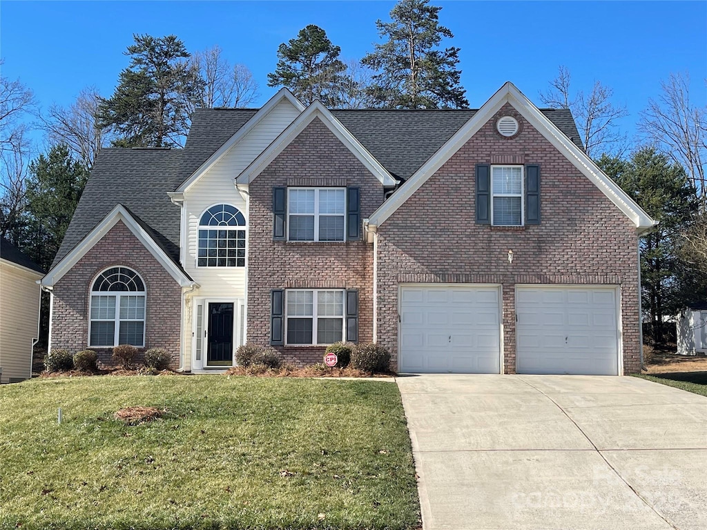 traditional-style house featuring a front yard, brick siding, and driveway