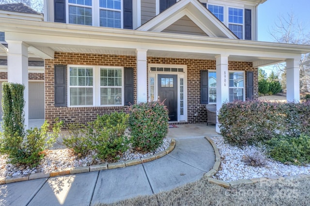 entrance to property featuring covered porch and brick siding