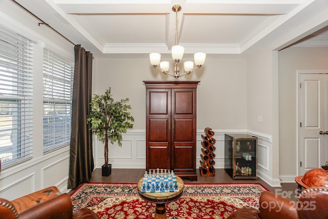 sitting room featuring a chandelier, a decorative wall, a wainscoted wall, wood finished floors, and crown molding