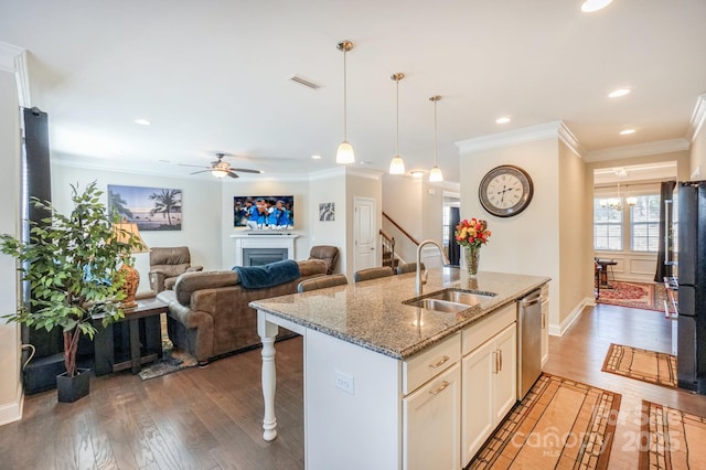 kitchen featuring light stone counters, a sink, visible vents, dishwasher, and a center island with sink