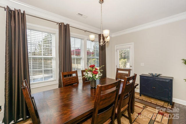 dining area with crown molding, visible vents, an inviting chandelier, wood finished floors, and baseboards