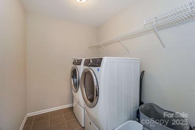 washroom featuring laundry area, dark tile patterned floors, washing machine and clothes dryer, and baseboards