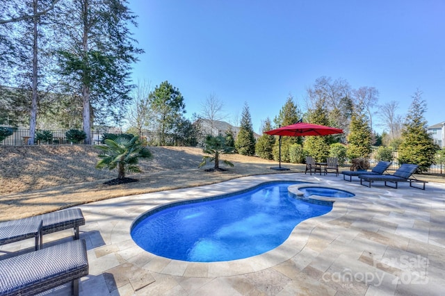 view of pool with a patio area, fence, and a pool with connected hot tub