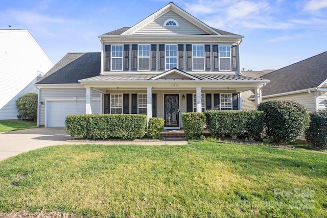 view of front of home featuring a porch, concrete driveway, a front yard, a standing seam roof, and a garage