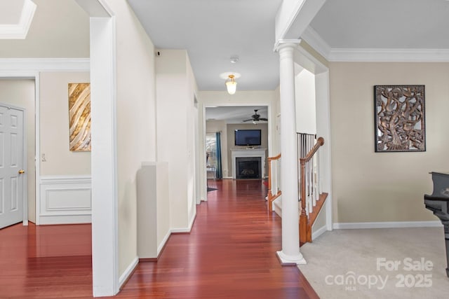 hall featuring decorative columns, ornamental molding, wood finished floors, baseboards, and stairs