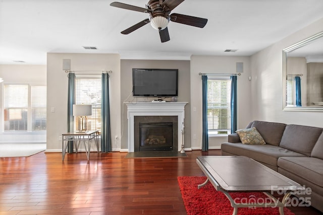 living area with a fireplace with flush hearth, wood finished floors, visible vents, and baseboards