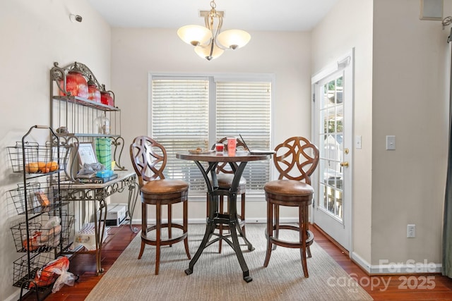 dining space with a chandelier, baseboards, and wood finished floors