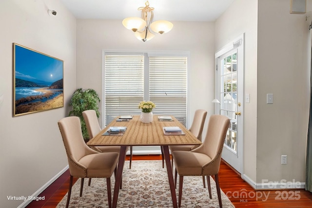 dining space with baseboards, wood finished floors, and an inviting chandelier