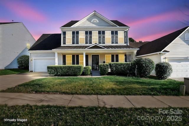 view of front of house with driveway, a standing seam roof, covered porch, and a lawn