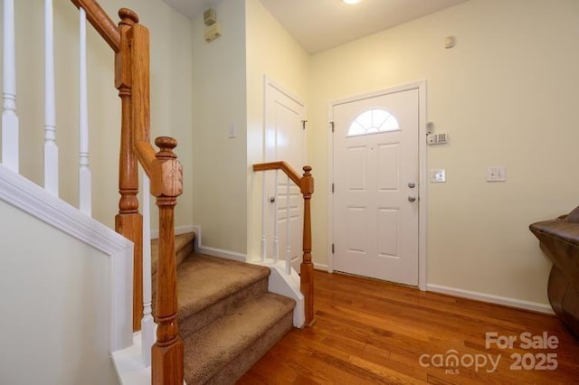 foyer entrance featuring stairway, wood finished floors, and baseboards