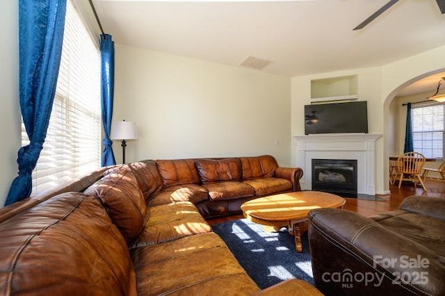 living room with a fireplace with flush hearth, a ceiling fan, and wood finished floors