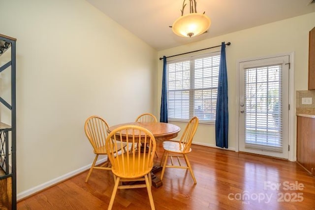 dining space featuring baseboards, vaulted ceiling, and wood finished floors