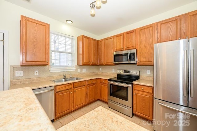 kitchen with light tile patterned floors, stainless steel appliances, a sink, light countertops, and decorative backsplash