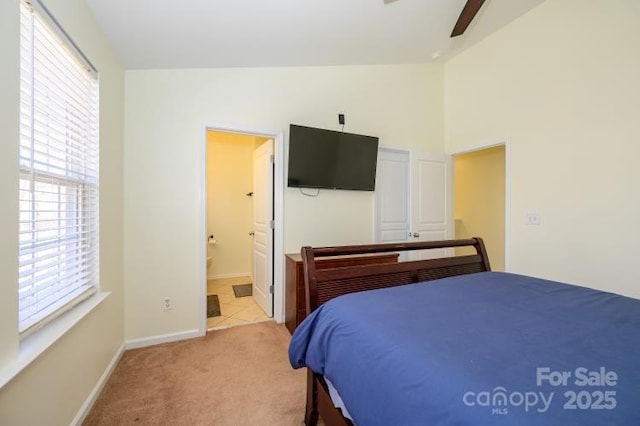 bedroom featuring connected bathroom, light carpet, a ceiling fan, baseboards, and vaulted ceiling