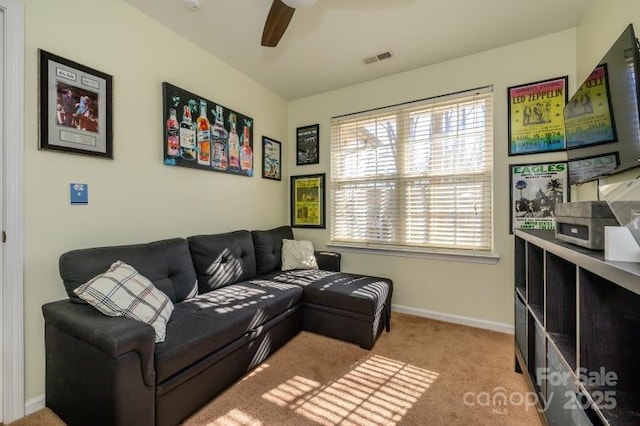 living room featuring light colored carpet, visible vents, ceiling fan, and baseboards