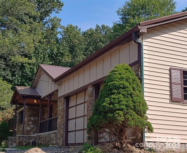 view of side of property with stone siding, metal roof, and board and batten siding