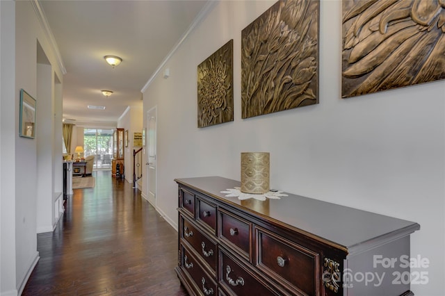 hallway featuring dark wood-style floors, visible vents, crown molding, and baseboards