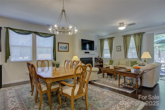 dining area with ornamental molding, dark wood finished floors, a fireplace, and baseboards