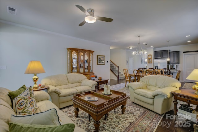 living area with stairs, visible vents, a ceiling fan, and wood finished floors