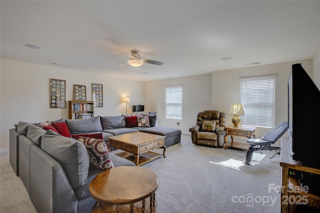 living room with a ceiling fan, visible vents, and light colored carpet