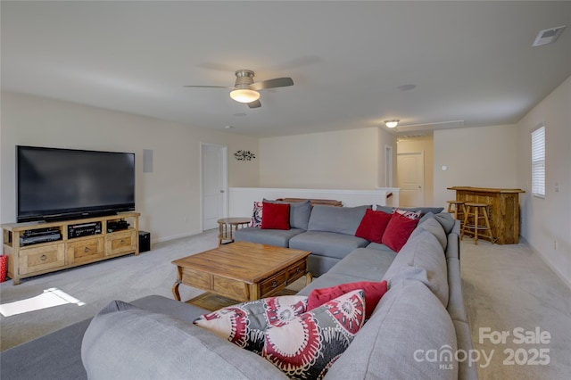 living room with light carpet, a ceiling fan, visible vents, and baseboards