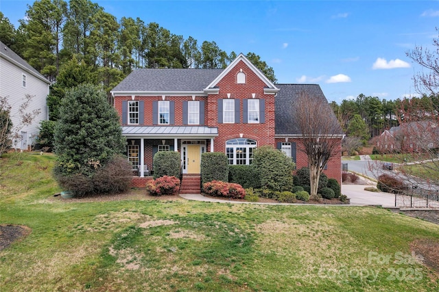 colonial inspired home with a front yard, brick siding, and roof with shingles