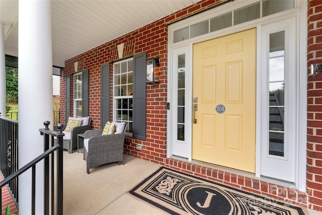 view of exterior entry with a porch and brick siding