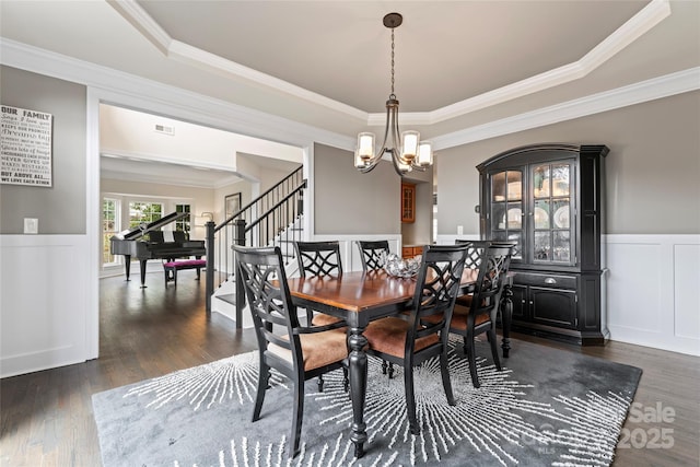 dining area featuring a chandelier, dark wood-style flooring, visible vents, stairway, and wainscoting