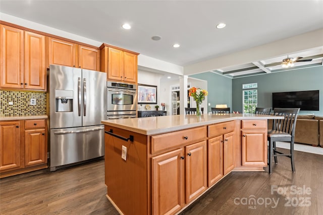 kitchen with dark wood-style flooring, stainless steel appliances, light countertops, open floor plan, and a kitchen island