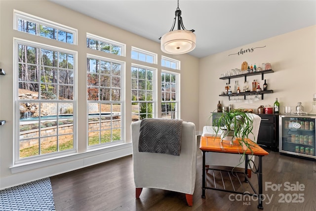 sitting room with wine cooler, dark wood finished floors, and a dry bar