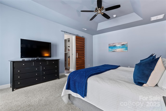 bedroom featuring a barn door, baseboards, a raised ceiling, a ceiling fan, and carpet floors