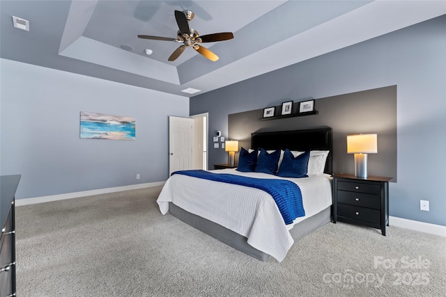 bedroom featuring carpet floors, a raised ceiling, visible vents, ceiling fan, and baseboards