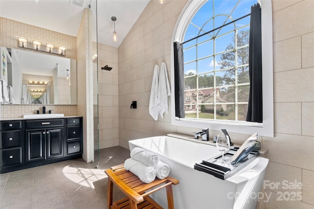 full bathroom featuring lofted ceiling, tile walls, tiled shower, a soaking tub, and tile patterned floors