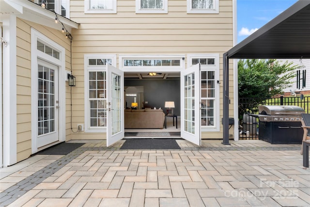 view of exterior entry with fence, french doors, and a patio