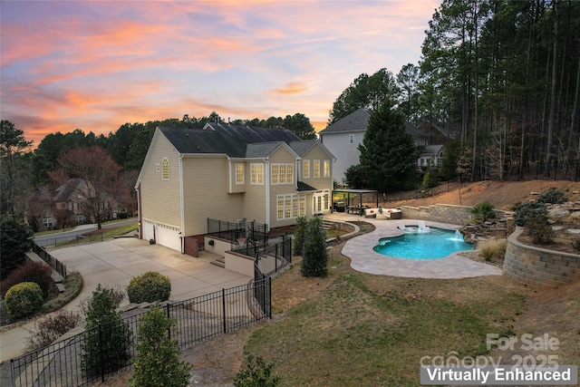 pool at dusk with a patio area, fence, and a fenced in pool