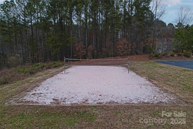 view of home's community featuring a wooded view and volleyball court