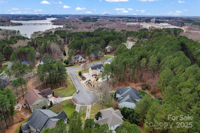 bird's eye view with a water view and a wooded view